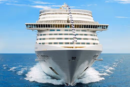 Large white cruise ship sailing on calm ocean waters under a partly cloudy sky.